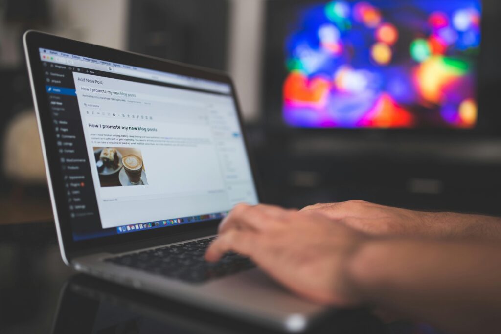 Hands typing on a laptop with a blog post visible, cozy indoor setting with colorful screen in background to promote digital marketing showing about social media